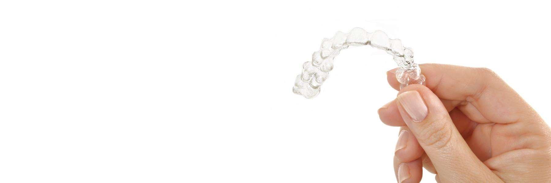 Hand holding up tray of Invisalign clear aligners in Bellevue, NE