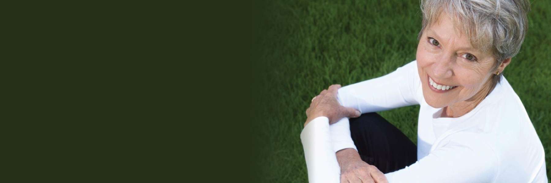 A woman with white hair sitting on the grass shows off her teeth in Nebraska