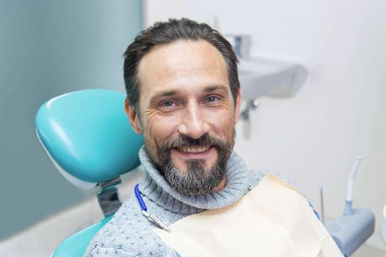 Man smiling confidently after getting a dental crown at Kennedy Dental in Bellevue, NE