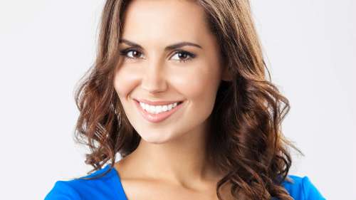 Close-up of a woman smiling, showing bright white teeth, representing the results of teeth whitening