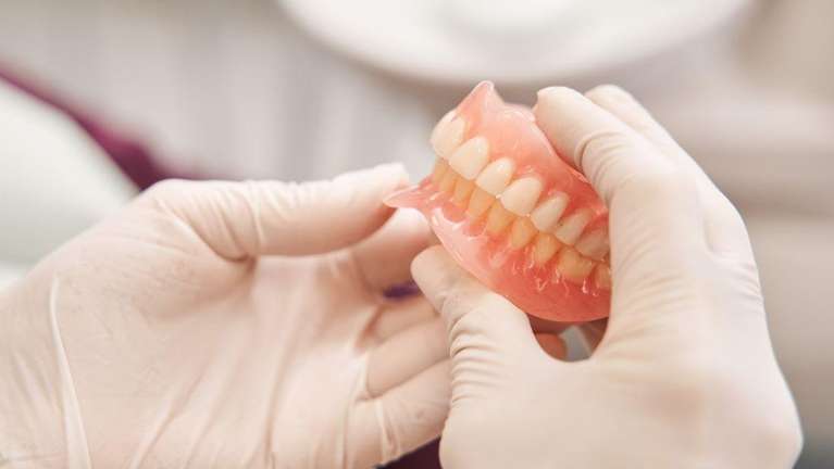 A pair of gloved hands holding dentures in Nebraska