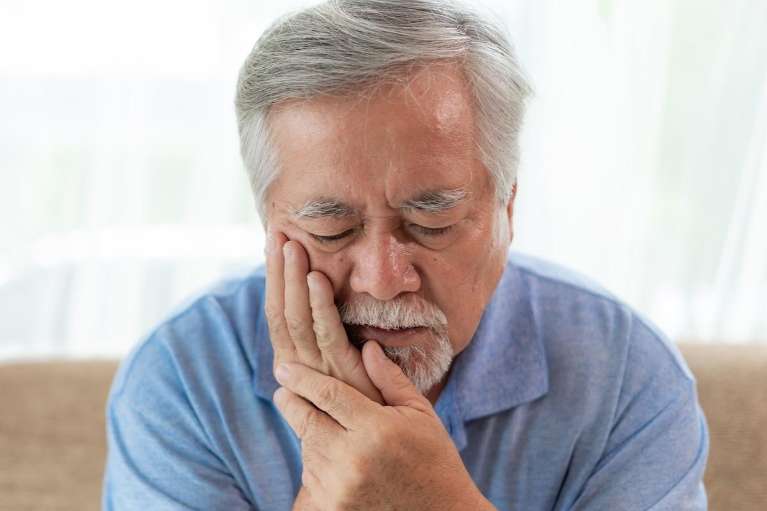Old man showing signs of tooth pain, a common symptom for needing a root canal in Bellevue, NE.