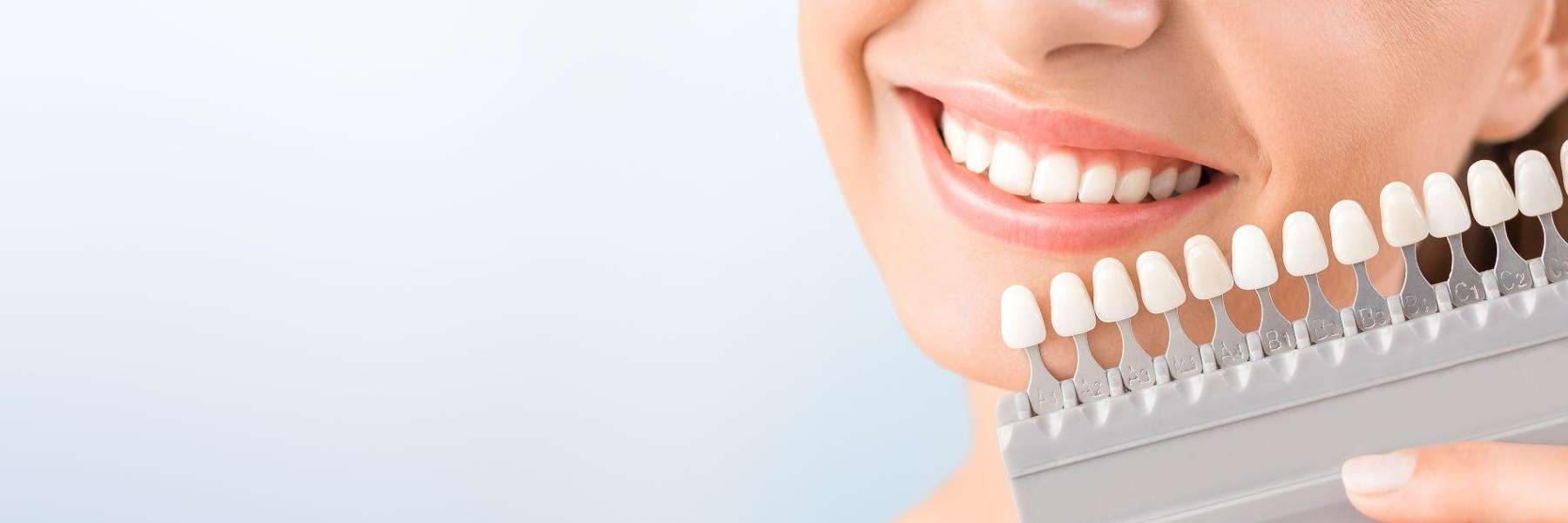 A woman smiles with her white teeth and holds a white teeth chart in Nebraska.