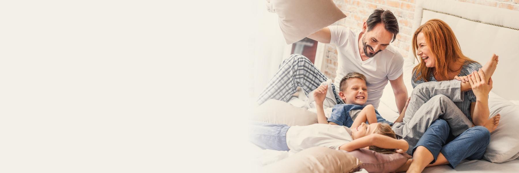 Family of four having pillow fight at home