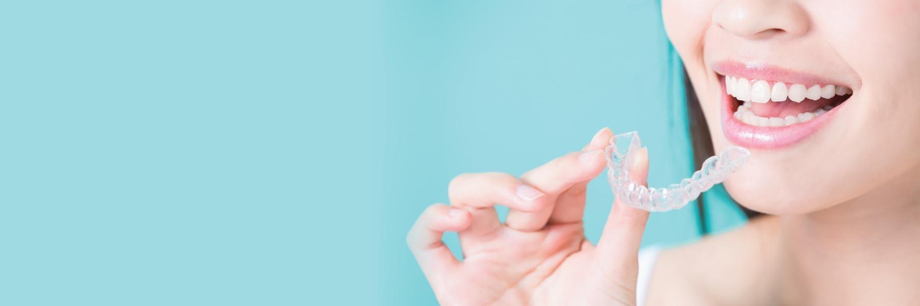 Dental patient holding up tray of Invisalign in Bellevue NE